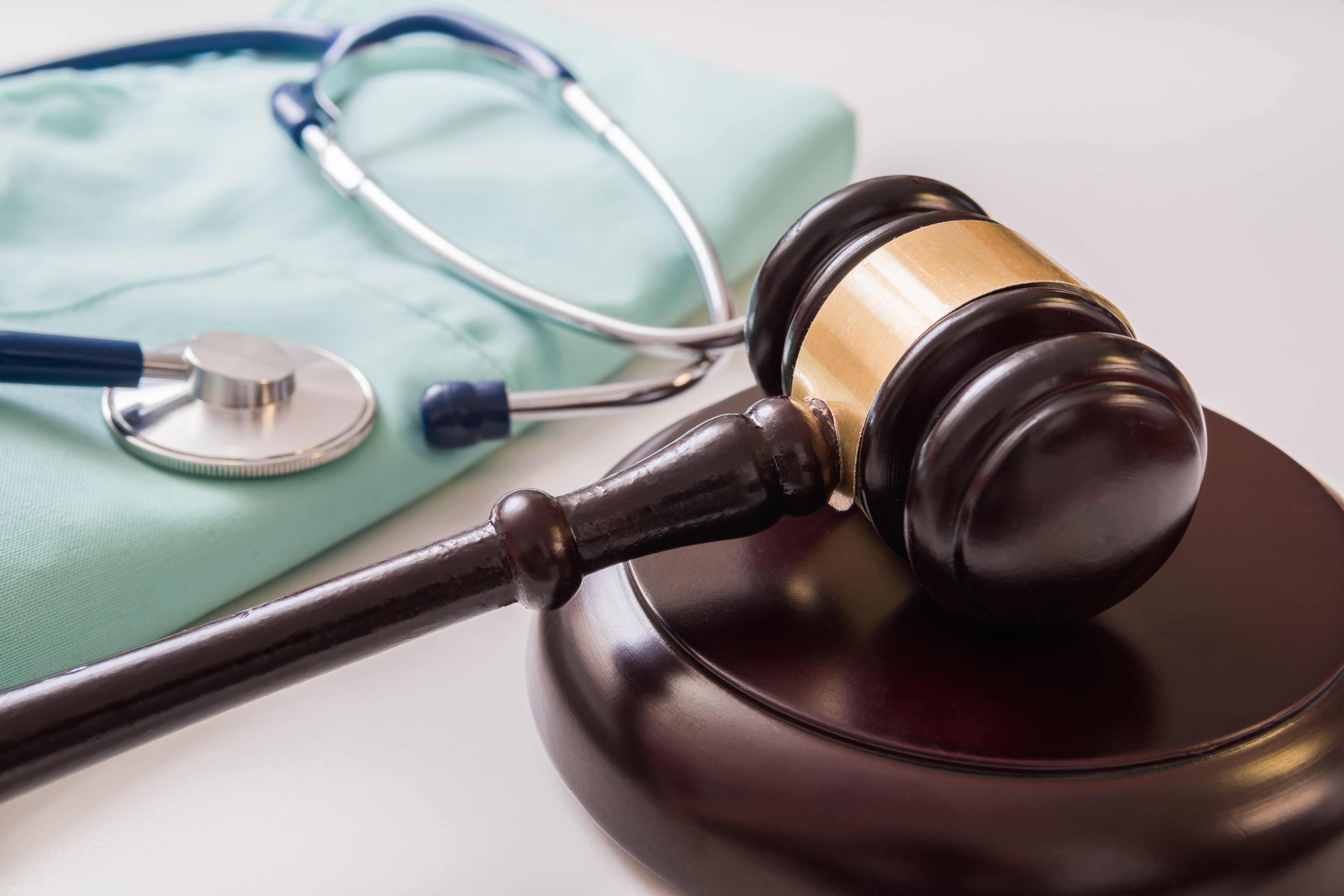 Gavel next to medical scrubs and a stethoscope